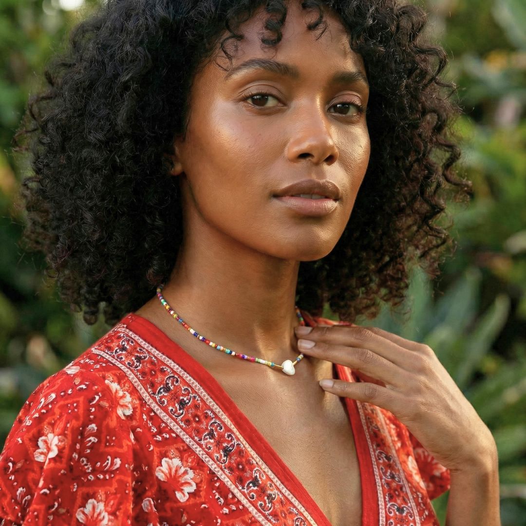 Woman wearing a red patterned top with a blurred green background