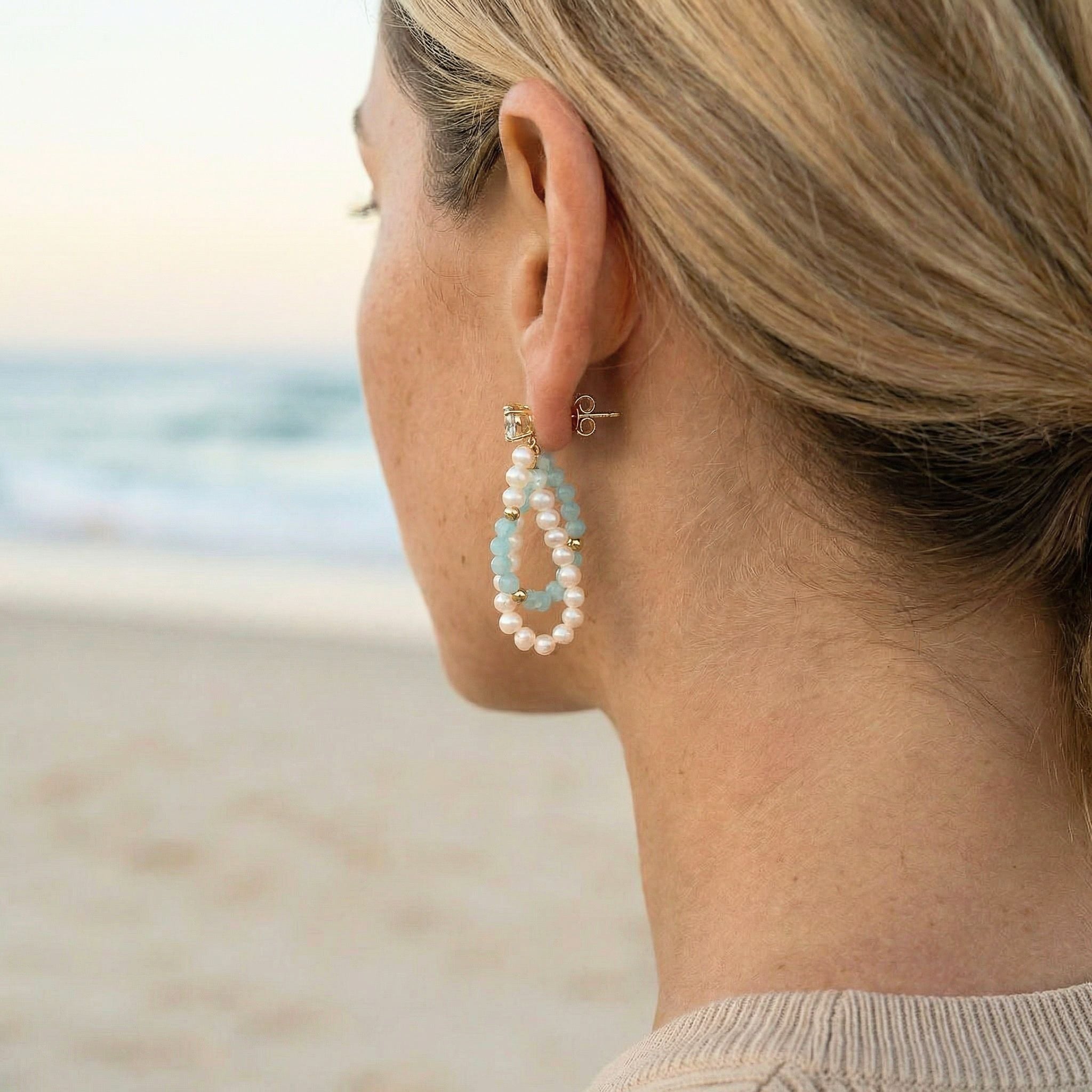 Woman wearing pearl earrings with a beach background