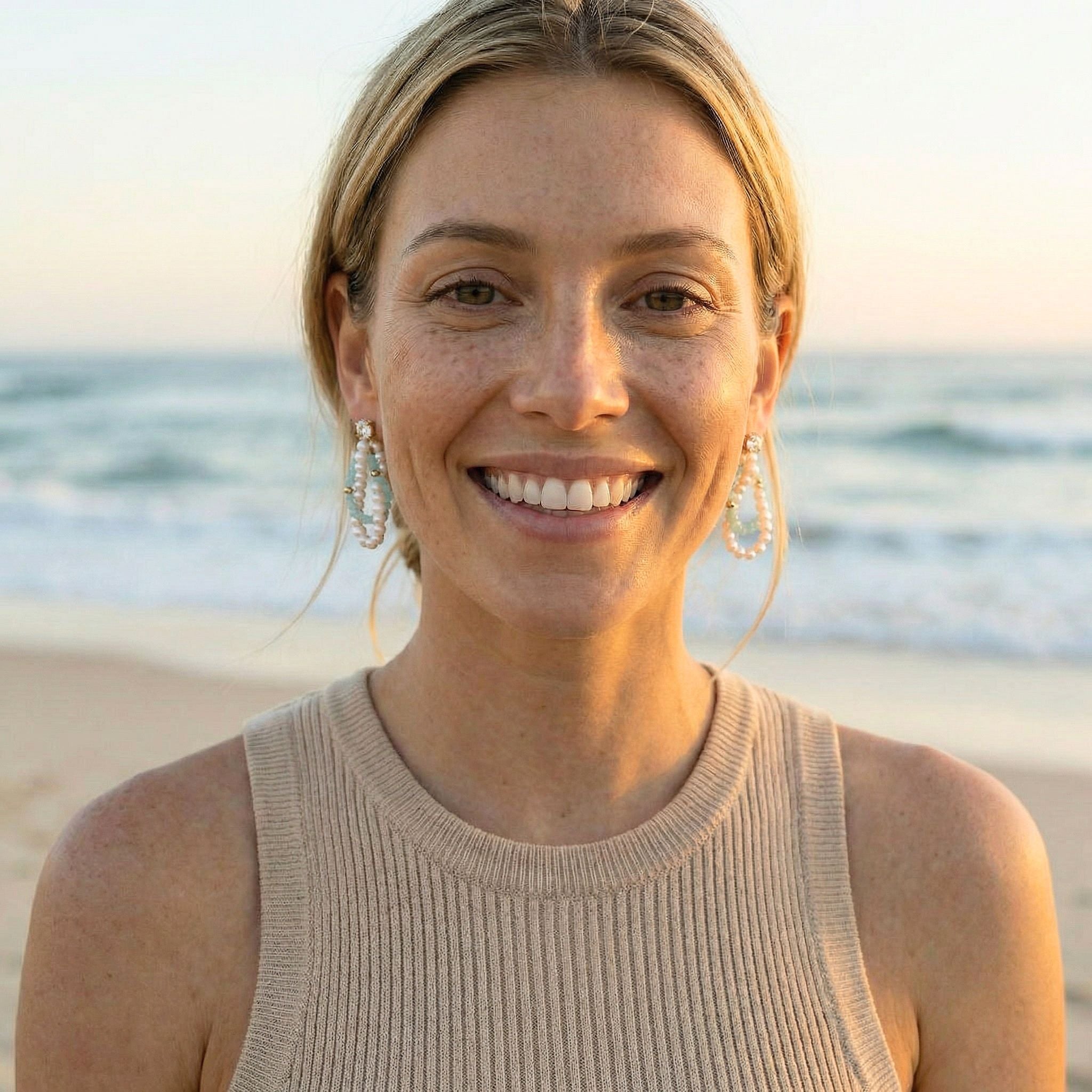 Woman smiling on a beach with ocean in the background