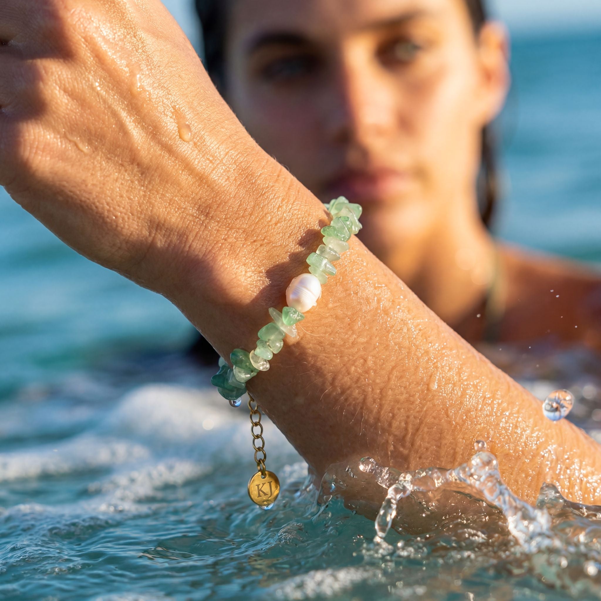 Person wearing a bracelet with water droplets on a beach