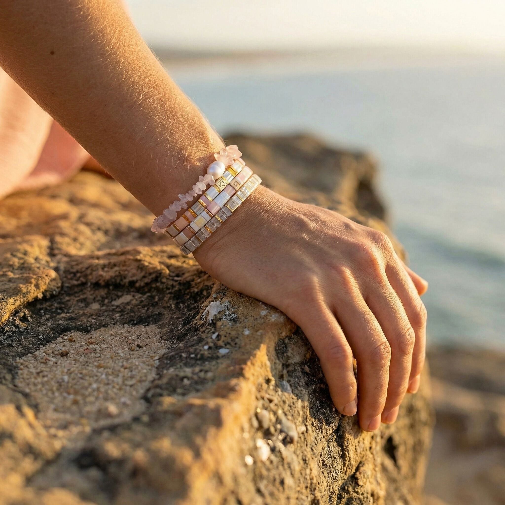 Hand wearing a bracelet on a rocky surface with a blurred natural background