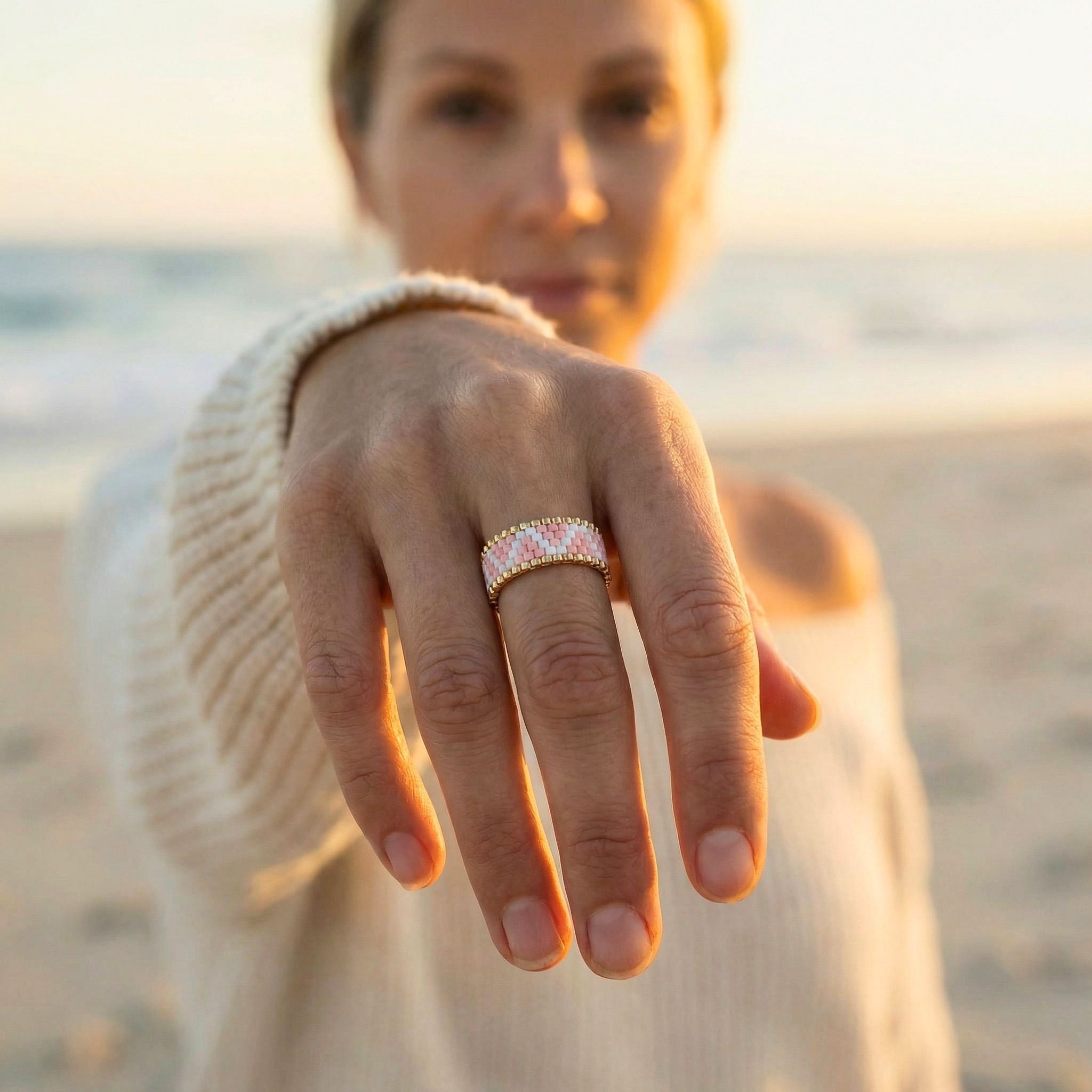 Woman on a beach holding out hand with a ring, blurred background