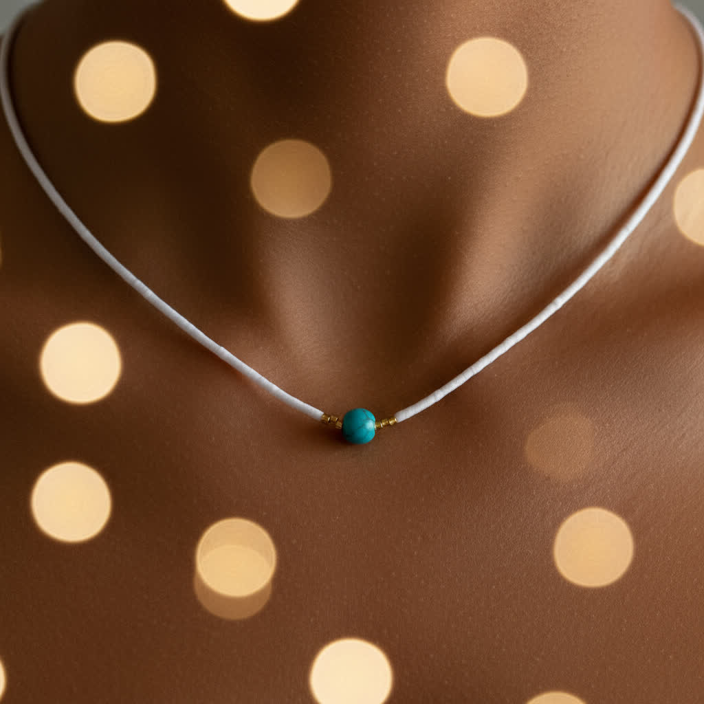 Necklace with a turquoise bead on a brown fabric background with light spots
