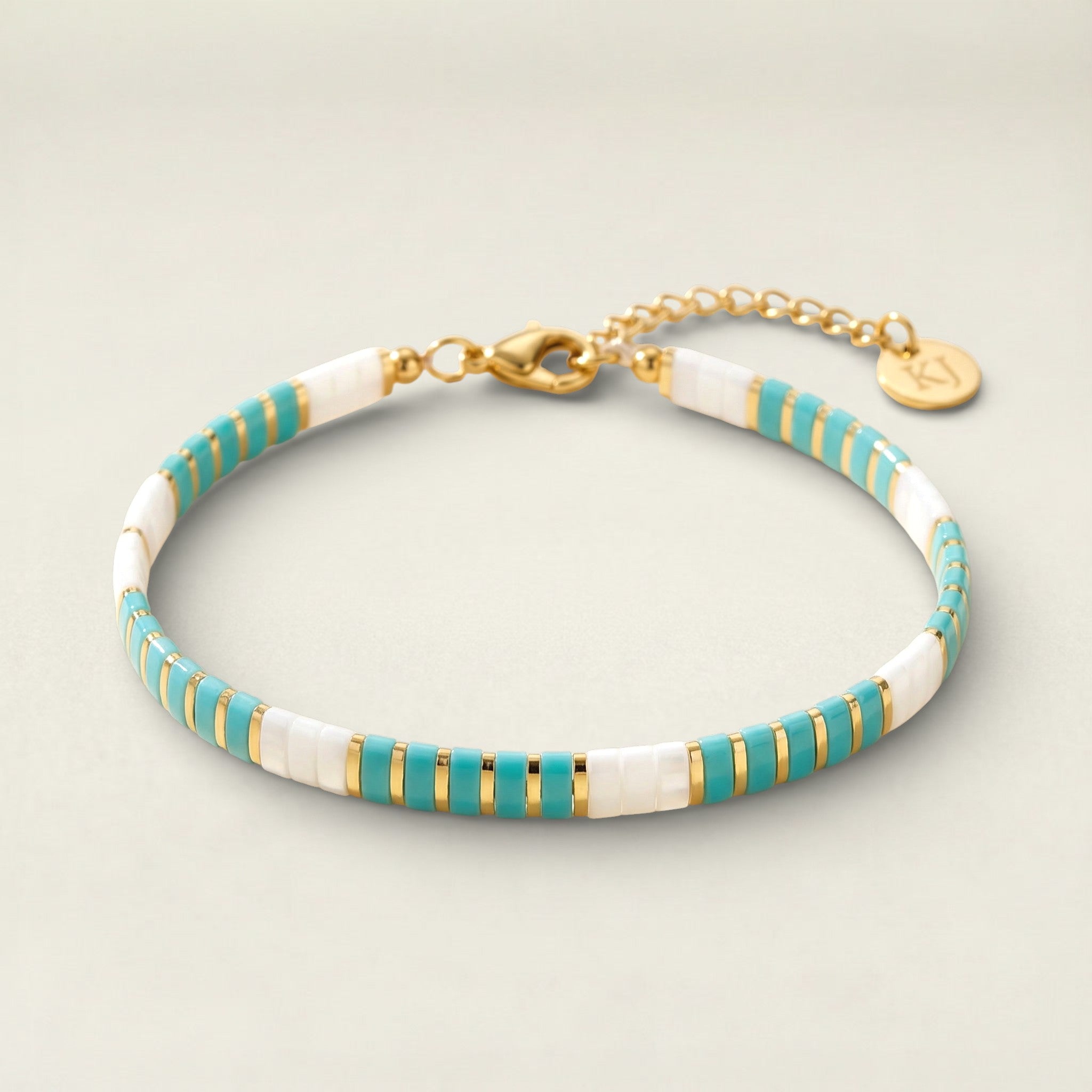 Bracelet with turquoise, gold, and white stripes on a beige background