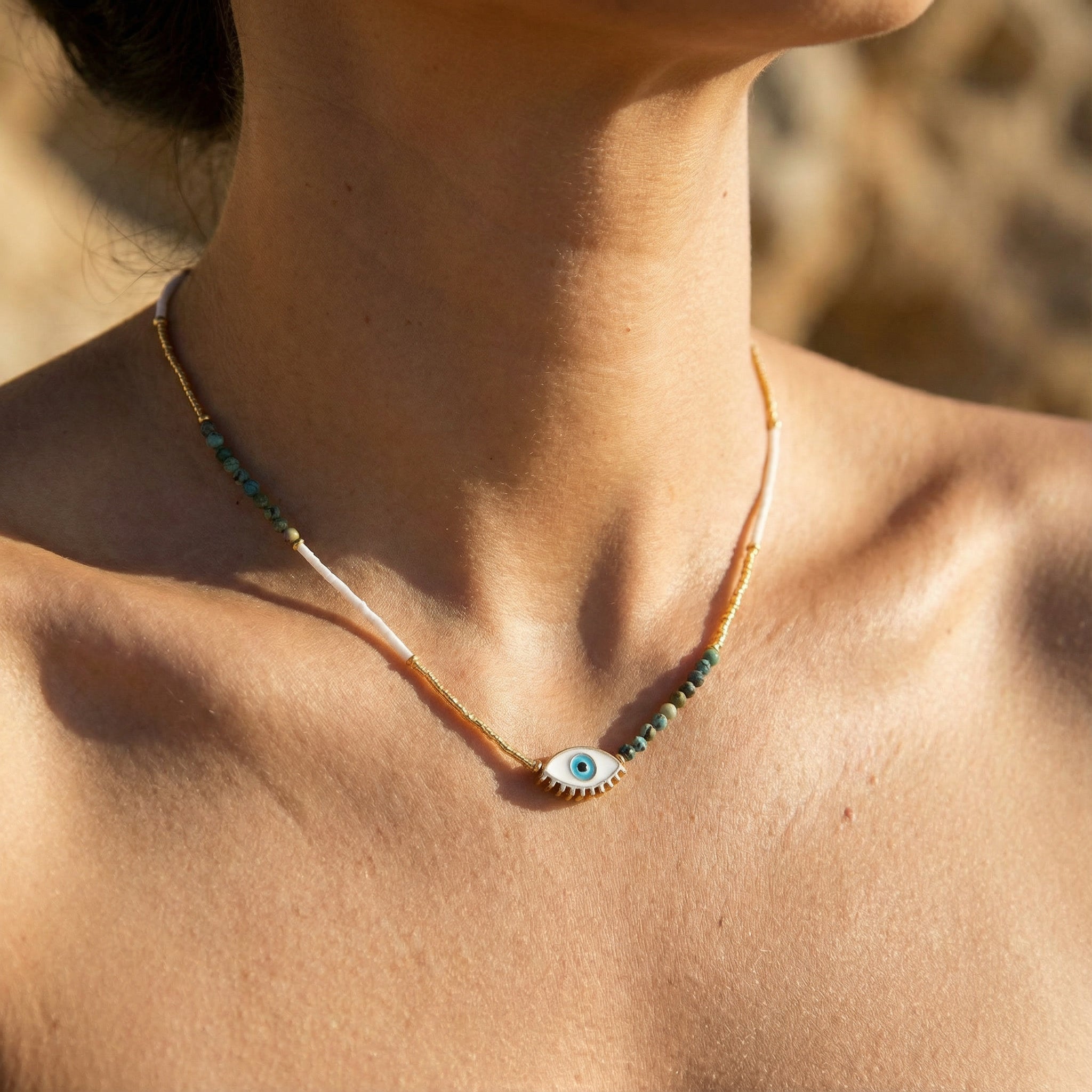 Necklace with an eye-shaped pendant on a person's neck against a blurred background