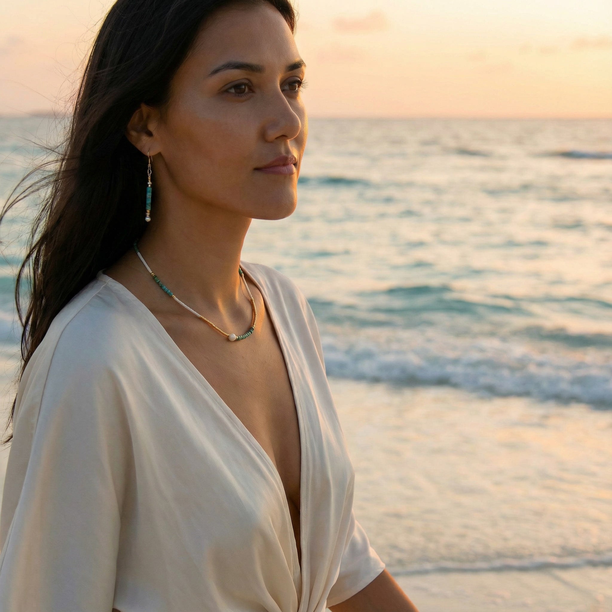 Woman in a white dress standing on a beach at sunset