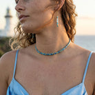 Woman wearing a blue beaded necklace and earrings outdoors