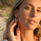 Woman adjusting pearl earrings on a beach