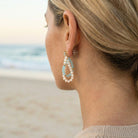 Woman wearing pearl earrings with a beach background