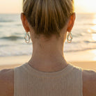 Person wearing earrings with a blurred beach background