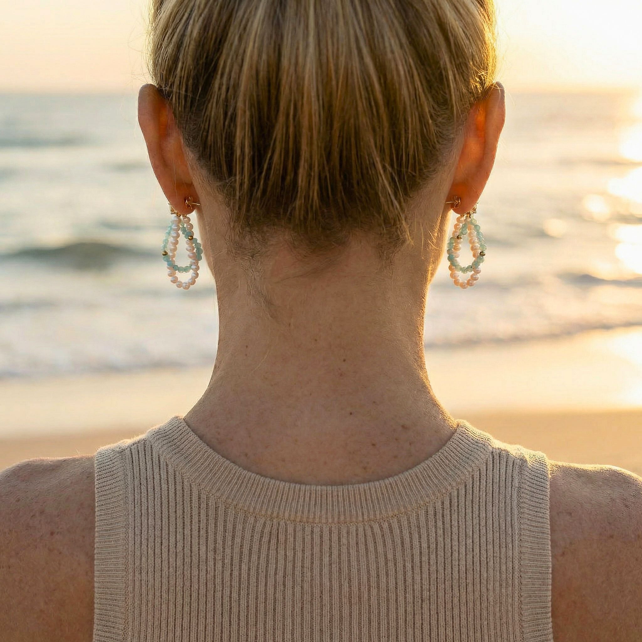 Person wearing earrings with a blurred beach background