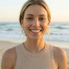 Woman smiling on a beach with ocean in the background