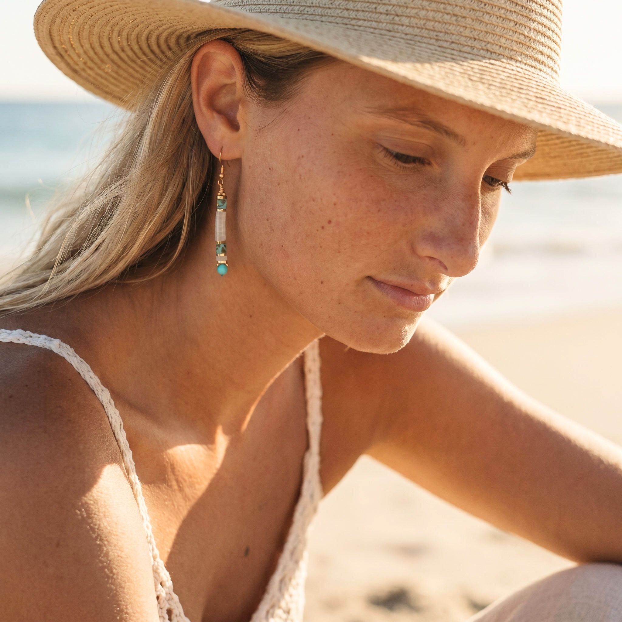 Woman wearing a straw hat and earrings on a beach