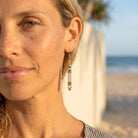 Close-up of a woman wearing earrings with a beach in the background