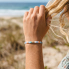 Person on a beach with a colorful beaded bracelet on wrist