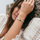 Woman wearing a bracelet with a stone wall background