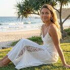 Woman in a white dress sitting on grass by the beach