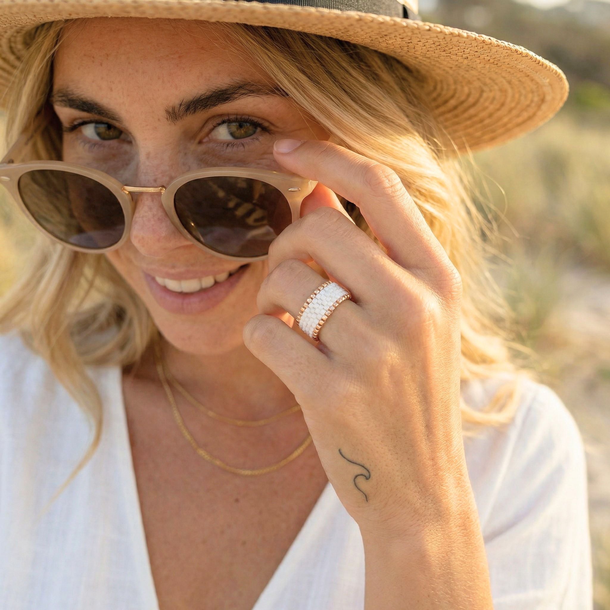 Woman wearing sunglasses and a hat with a blurred natural background