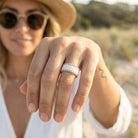 Close-up of a hand wearing a ring with a blurred natural background