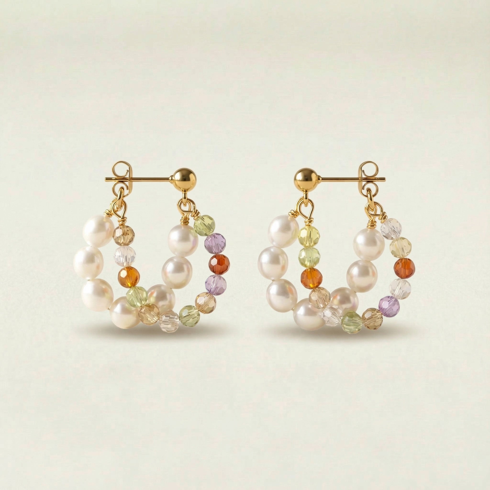 Pair of pearl and gemstone hoop earrings on a light background