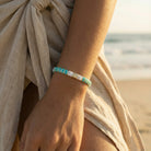 Person wearing a turquoise bracelet on a beach