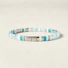 A beaded stretch bracelet featuring alternating turquoise, mint green, light blue, and silver metallic square beads, with a central silver clasp engraved with the initials 'RJ'.