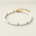 White bracelet with gold accents on a light gray background