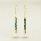Gold and turquoise earrings on a beige background