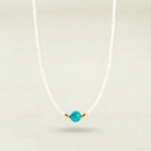 Necklace with a turquoise bead and gold accent on a light gray background