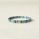 Multicolored beaded bracelet with a gold clasp on a beige background