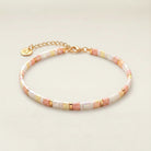 Multicolored beaded bracelet with gold chain on a light beige background