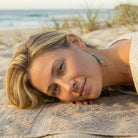 Woman lying on a towel at the beach with a blurred background