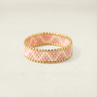 Pink beaded bracelet with gold accents on a light beige background