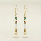 Gold earrings with cylindrical beads on a beige background